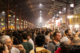 A modern food market bustling with people exploring vibrant stalls under warm lighting.