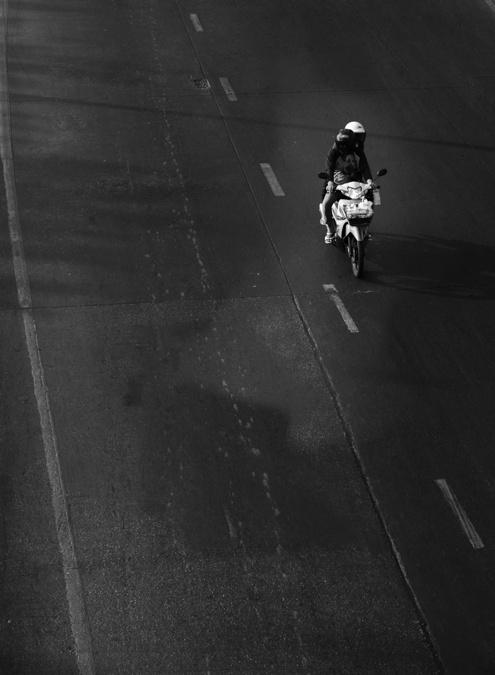 grayscale photo of man riding motorcycle on road