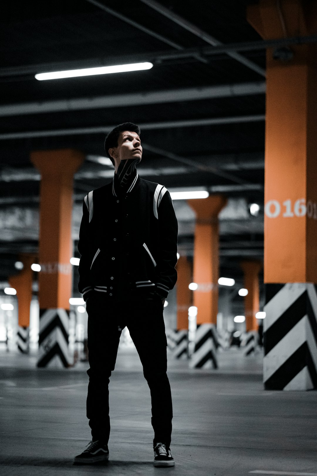 man in black jacket standing on gray pavement