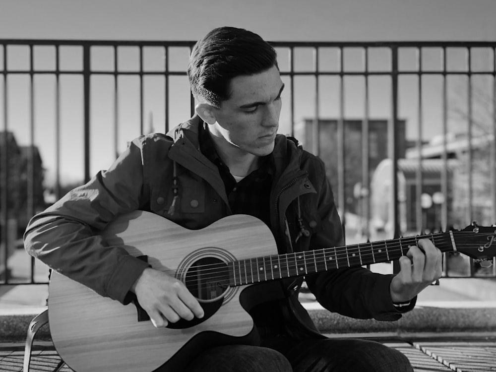 man in black jacket playing acoustic guitar