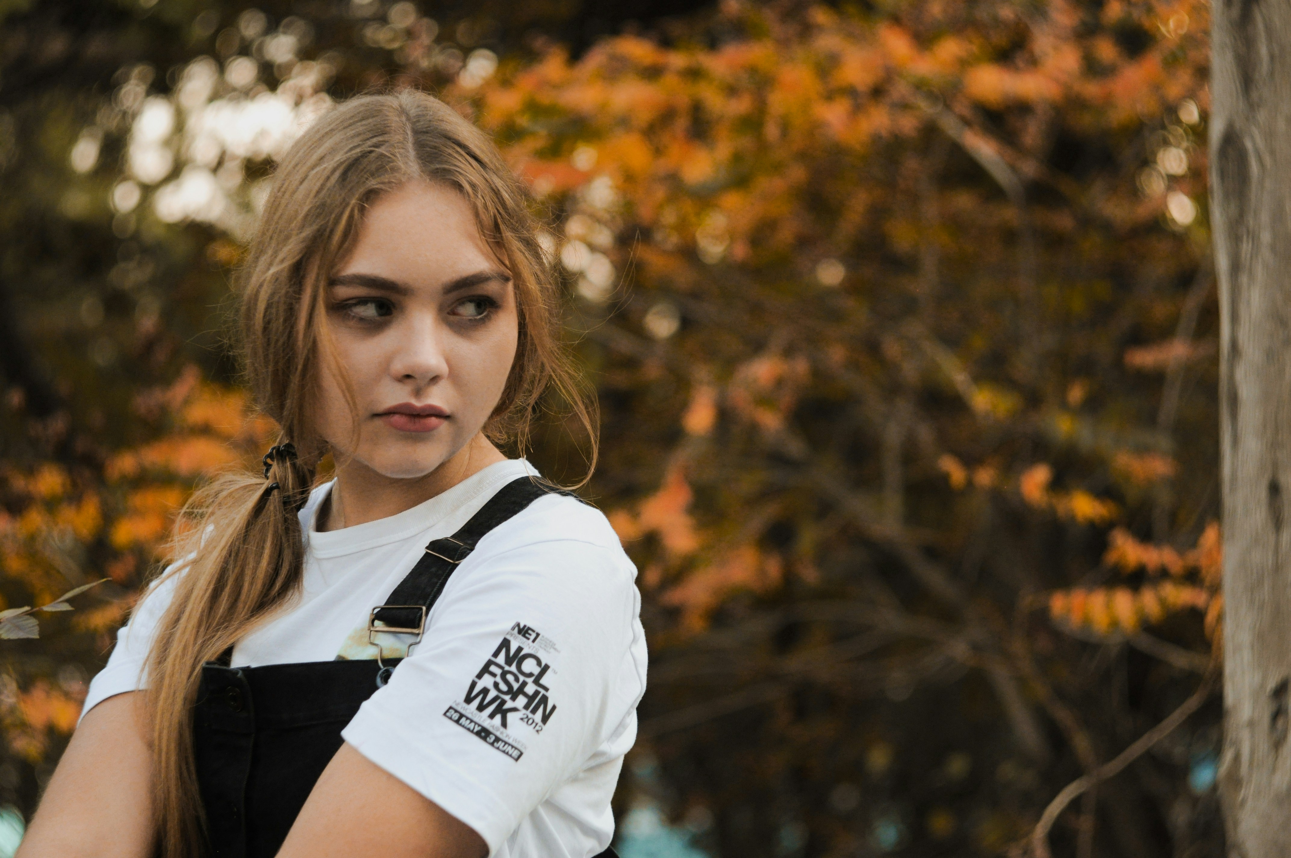 Young woman with blonde ponytail and overalls outdoors