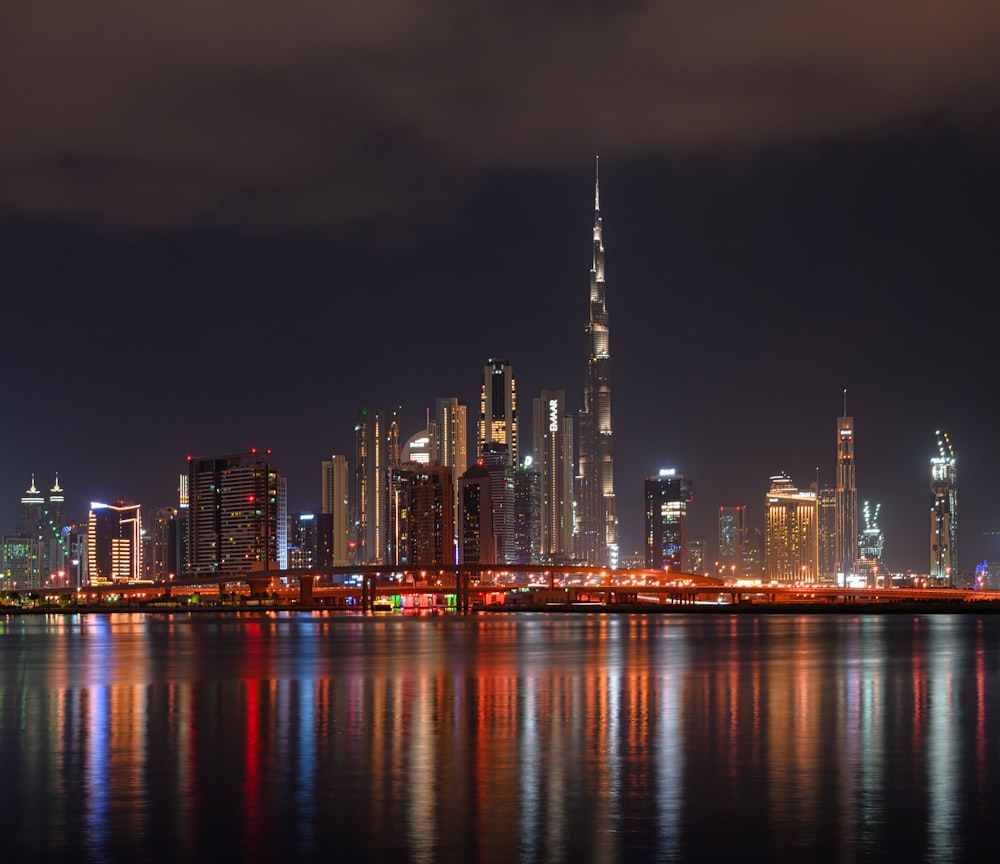 city skyline across body of water during night time