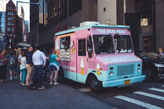A cheerful food truck with bright Snowflake Ice branding parked at a busy park with customers enjoying treats.