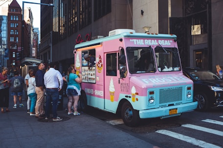 A cheerful food truck with bright Snowflake Ice branding parked at a busy park with customers enjoying treats.