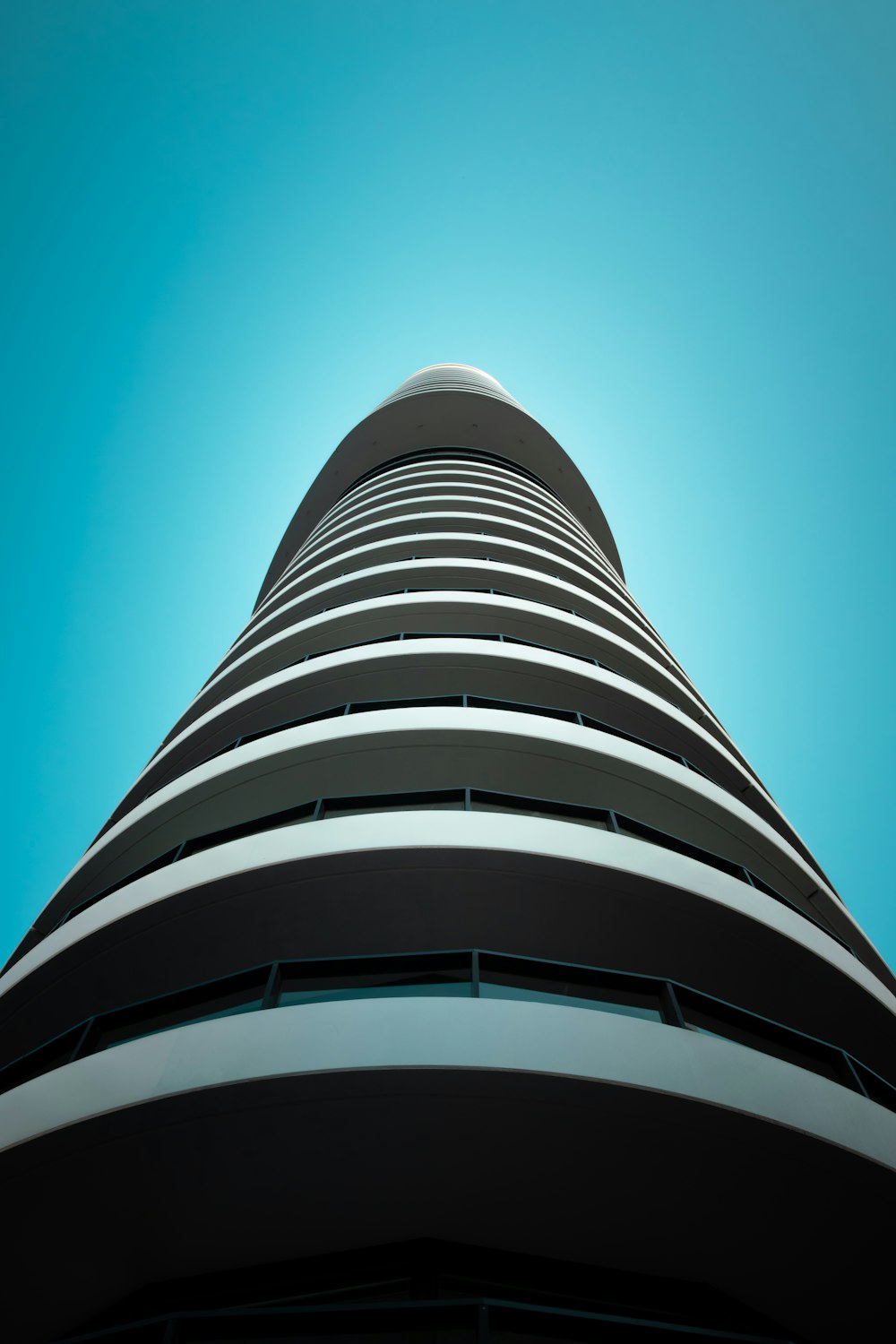 low angle photography of white and black concrete building under blue sky during daytime