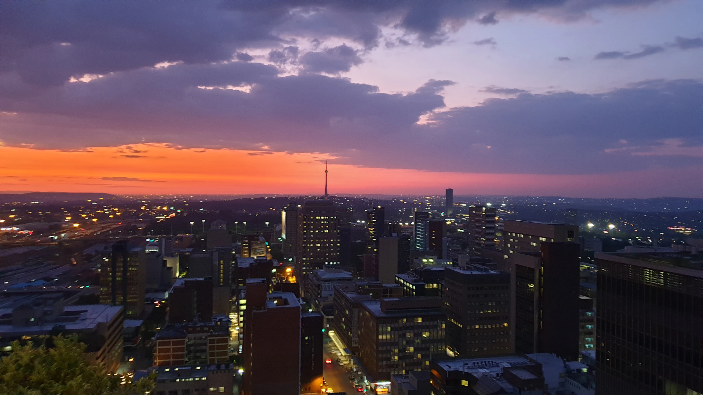Johannesburg skyline at dusk with city lights and a sunset sky