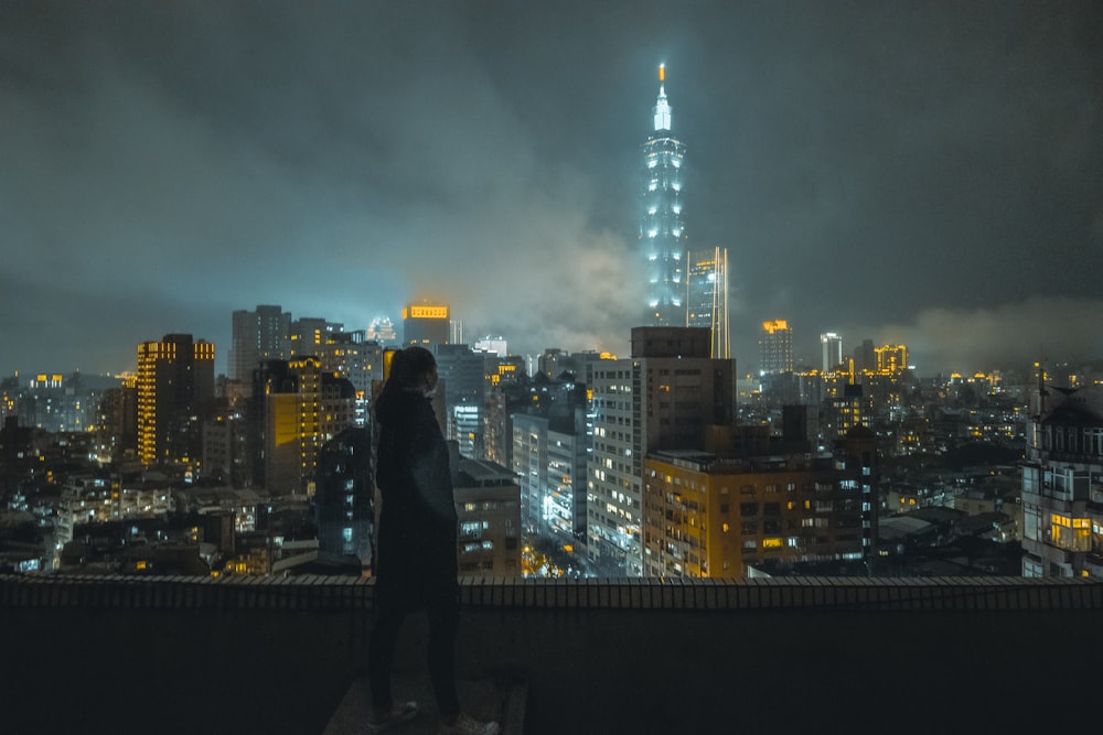 a woman standing on top of a building at night