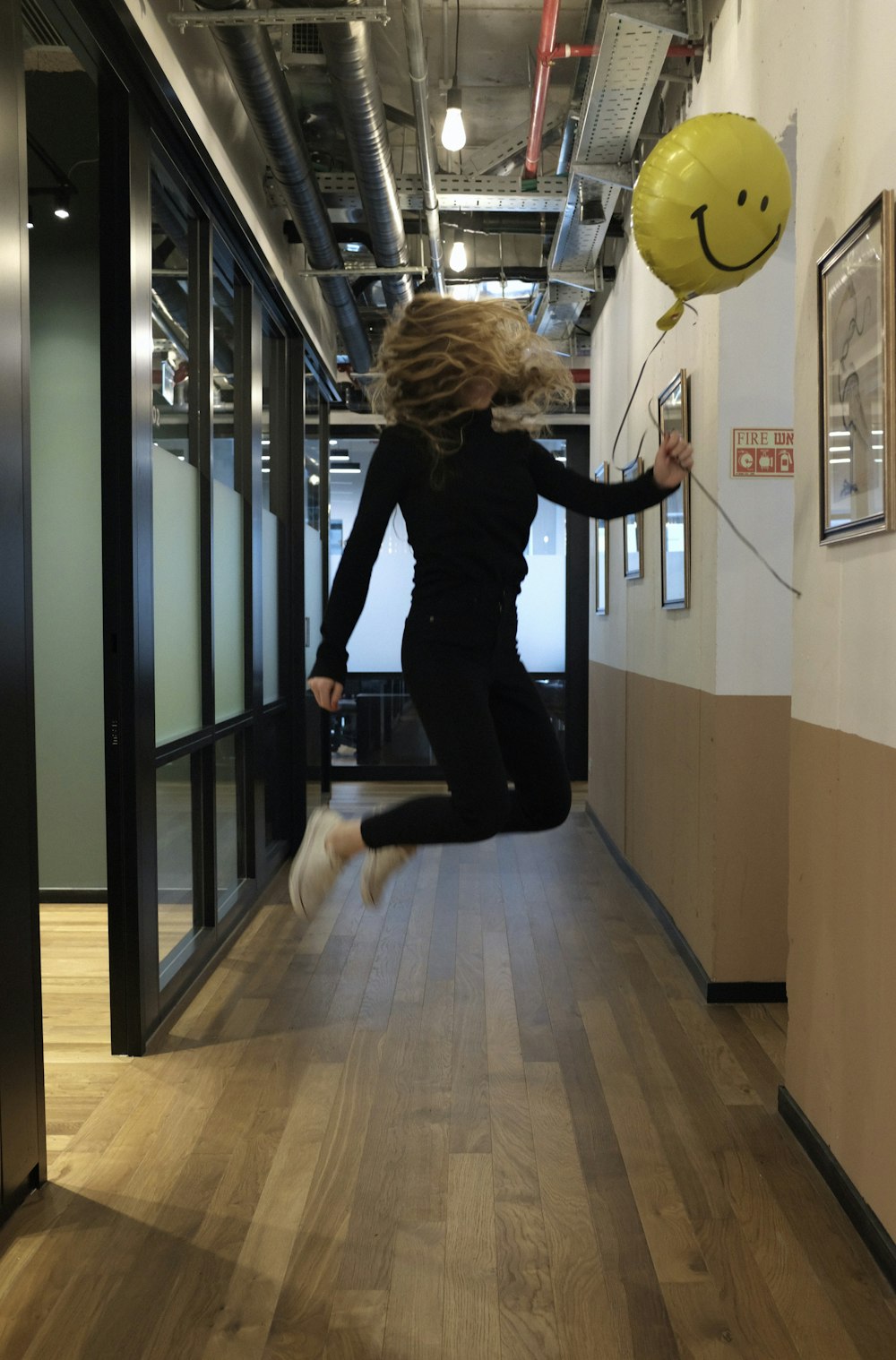 femme en chemise noire à manches longues et pantalon noir tenant une balle jaune