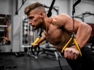 topless man in black pants holding black and yellow exercise equipment