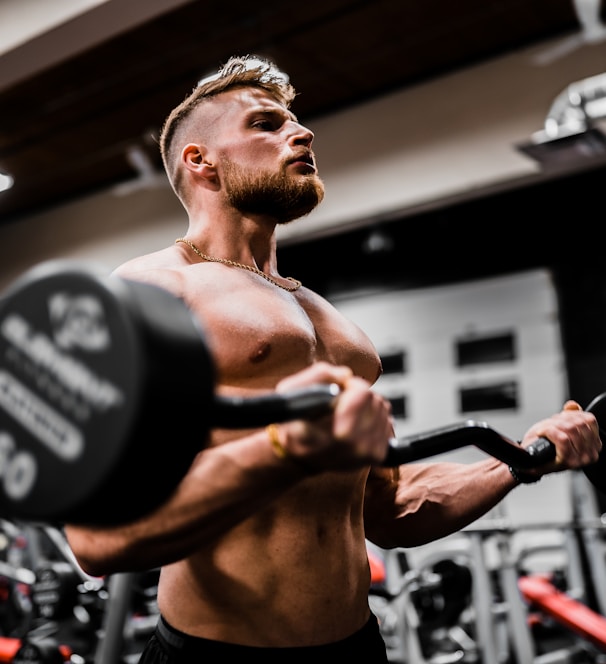 topless man in black shorts carrying black dumbbell