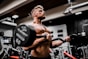topless man in black shorts carrying black dumbbell