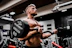topless man in black shorts carrying black dumbbell