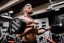 topless man in black shorts carrying black dumbbell
