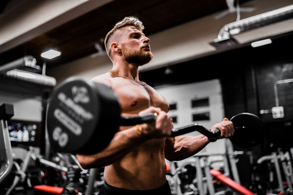 topless man in black shorts carrying black dumbbell