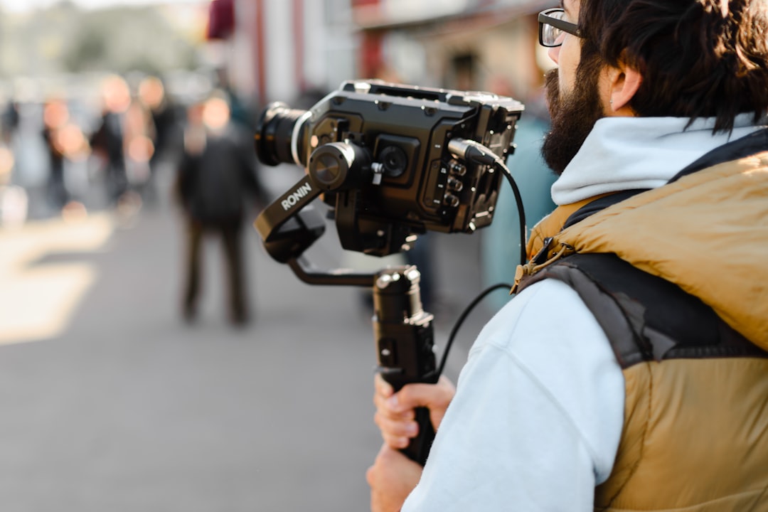 man in yellow jacket holding black dslr camera