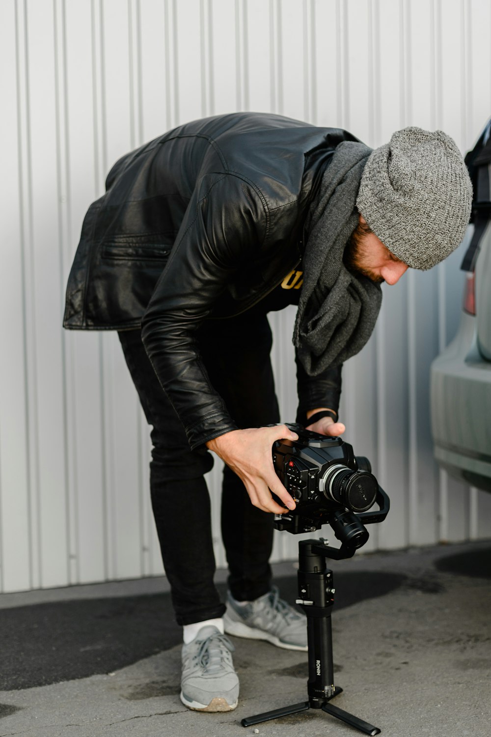 Hombre con chaqueta de cuero negro sosteniendo una cámara DSLR negra