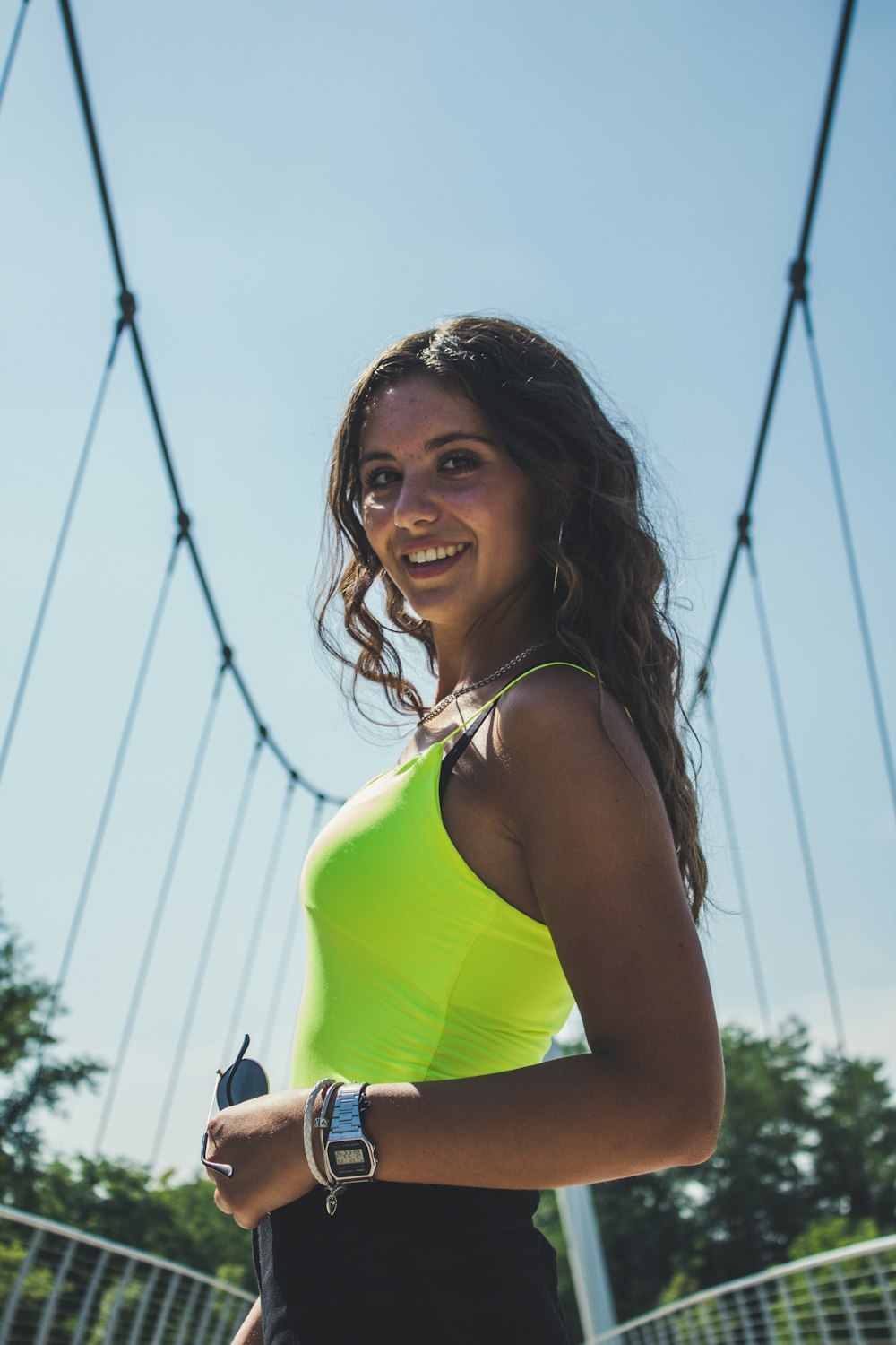 woman in yellow tank top holding black camera during daytime