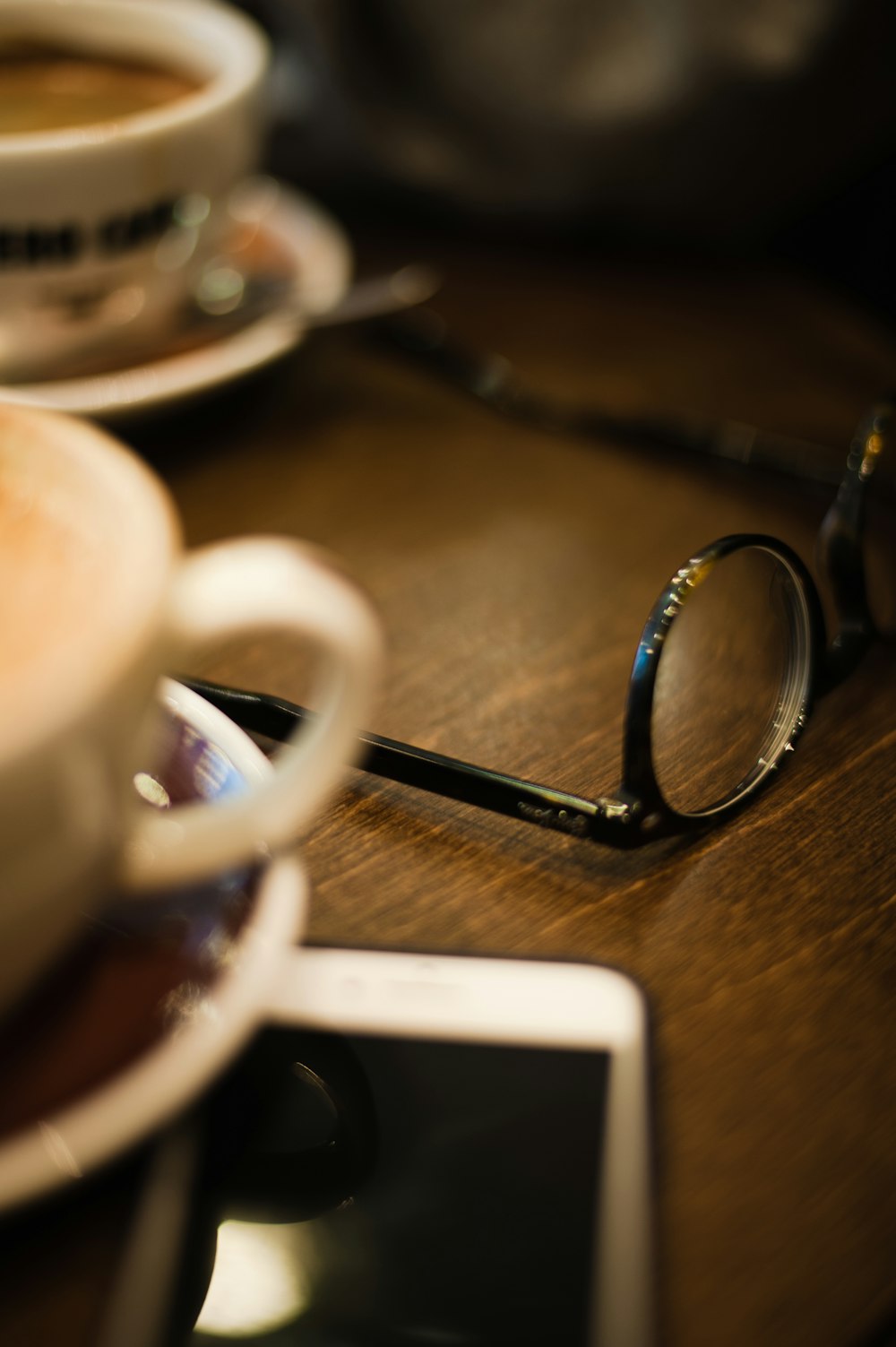 white ceramic mug beside silver iphone 6 on brown wooden table