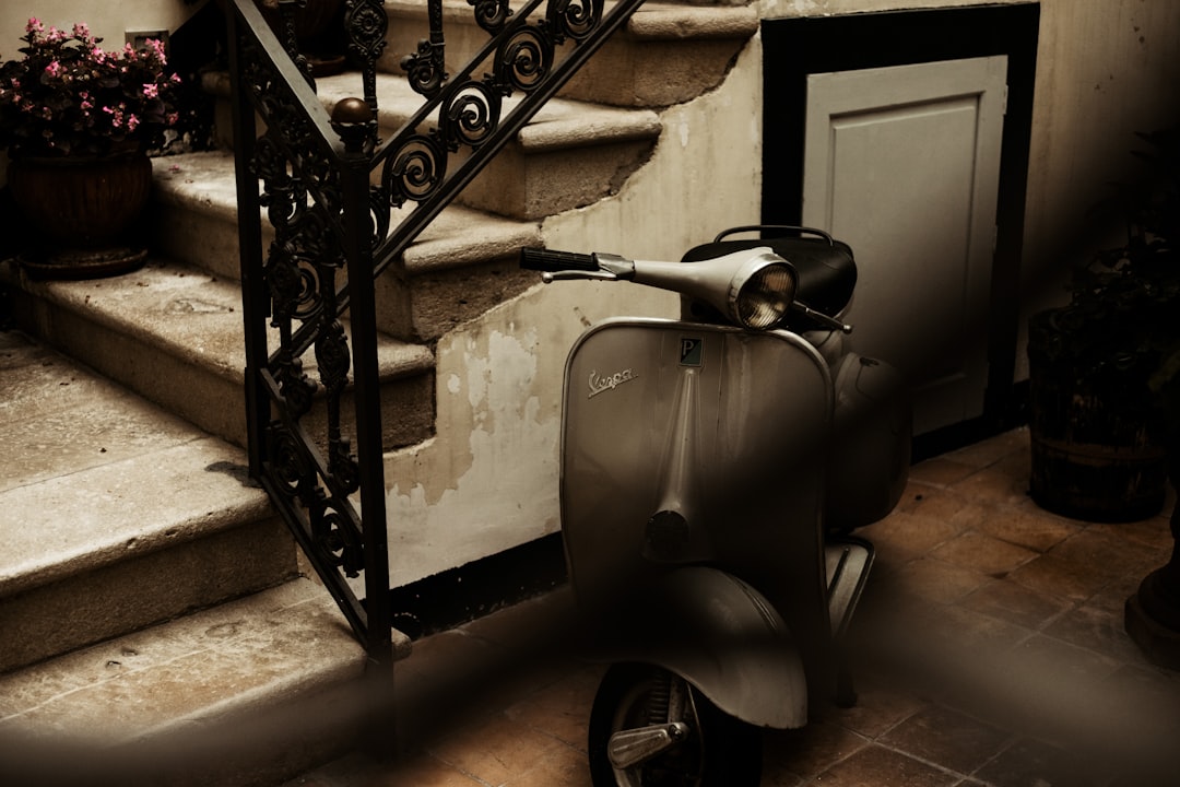 black and white motor scooter parked beside black metal railings