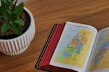 An open book with a map and travel accessories on a wooden table.