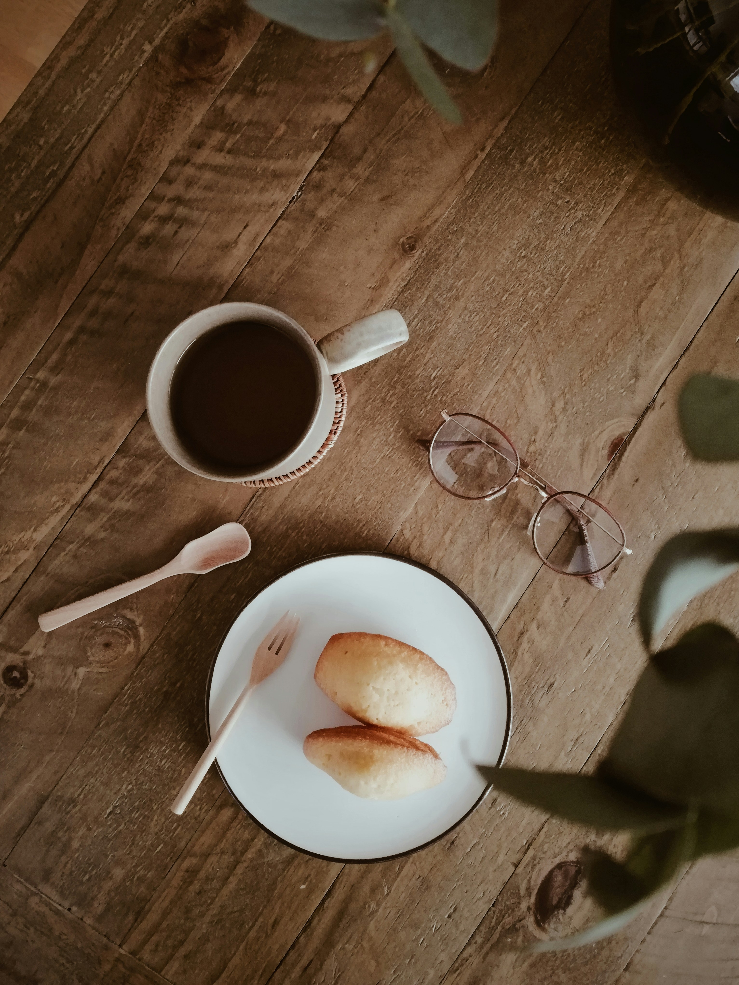 Tasse en céramique blanche à côté d’une cuillère en acier inoxydable sur une table en bois brun