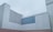 A minimalist architectural structure with clean, geometric lines and a modern aesthetic. The building features a stark contrast between light grey and darker grey panels, with a seamless, block-like design. The sky is overcast, adding to the monochromatic theme.