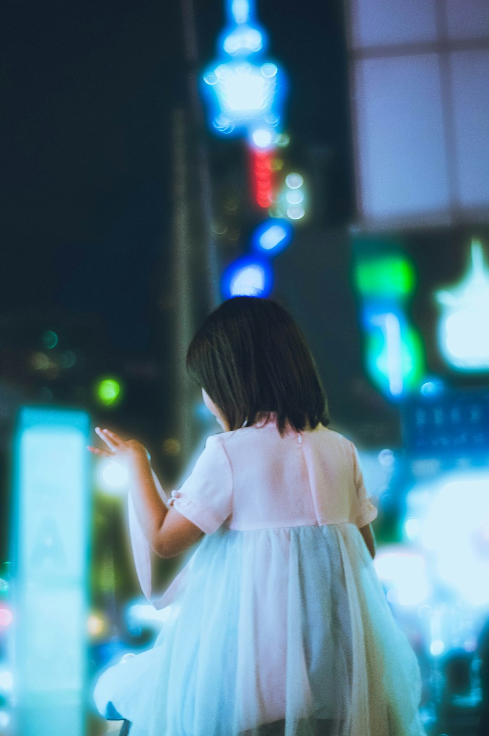 girl in white dress standing on street during night time