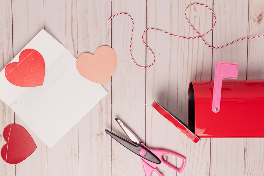 red and silver scissors on white wooden table