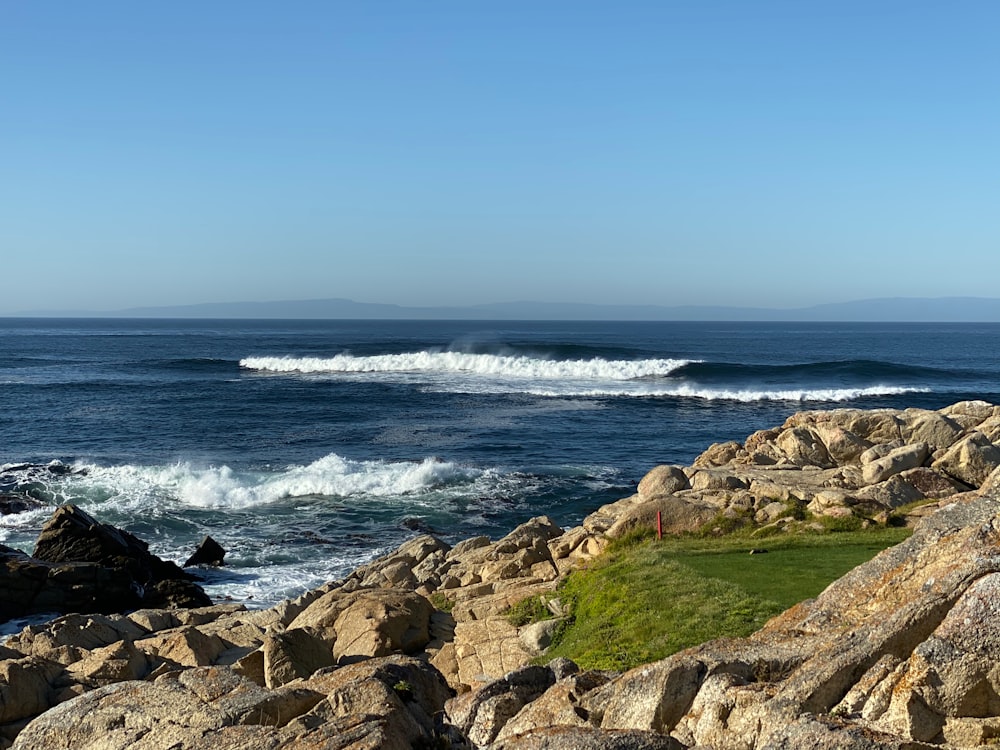 brown rocky shore with ocean waves crashing on shore during daytime