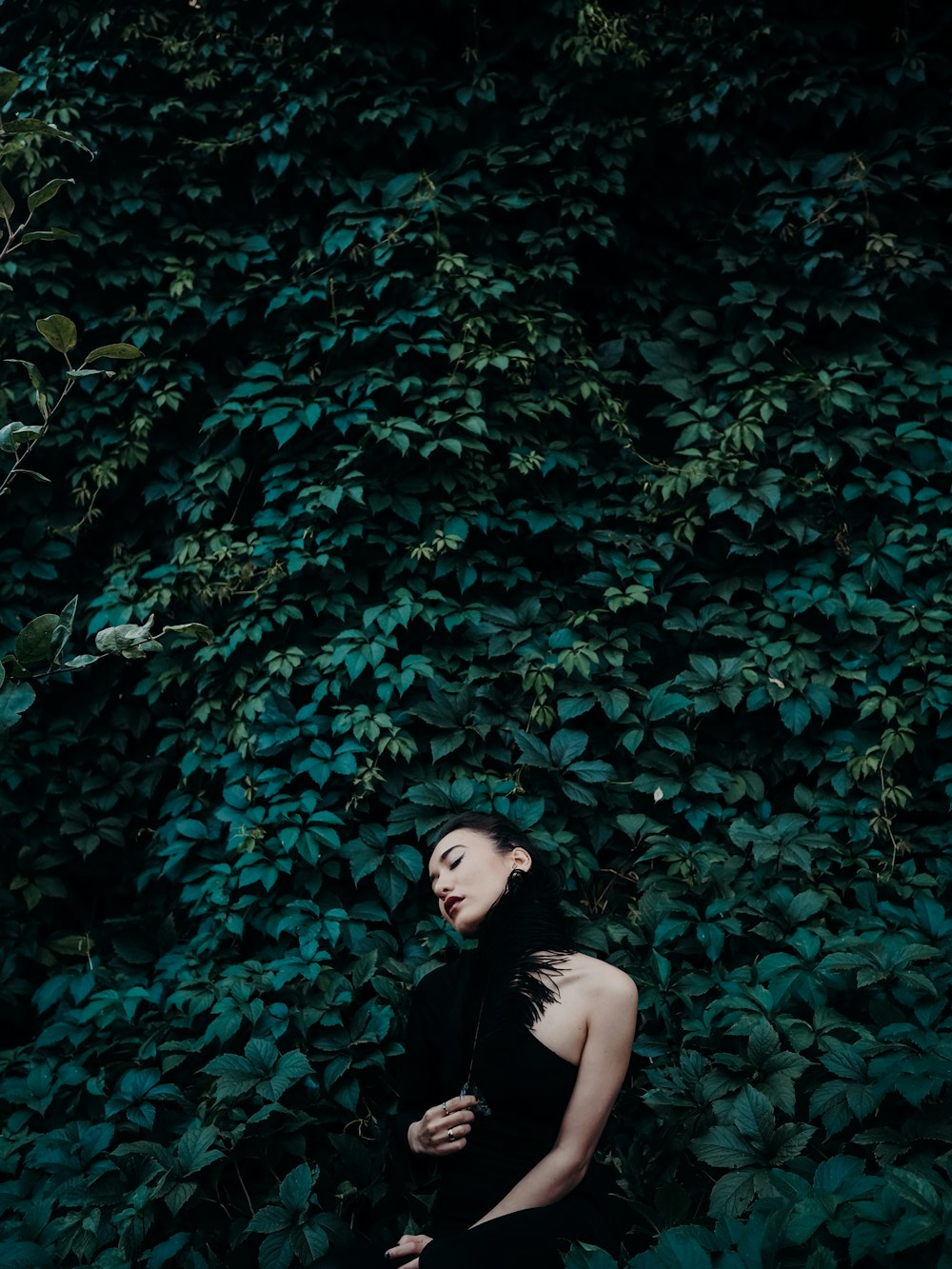 woman in black shirt standing beside green leaves