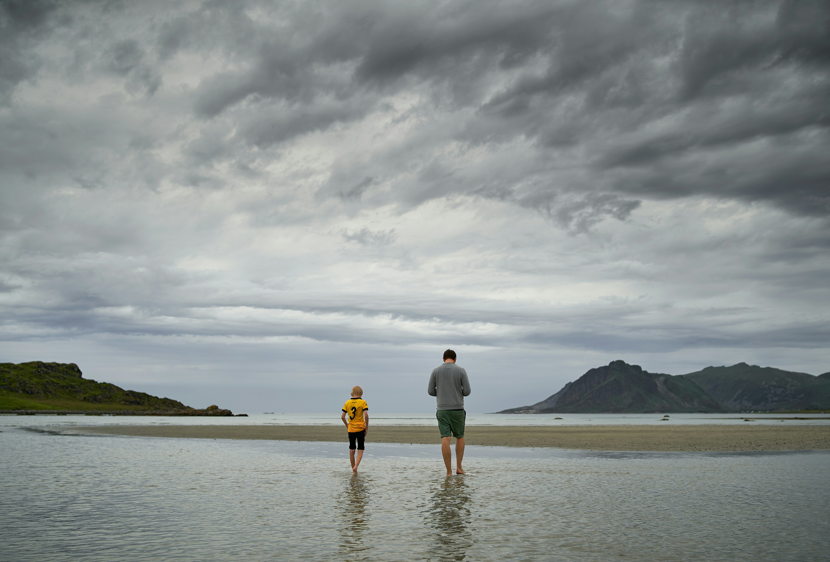 man and woman holding hands while walking on beach during daytime