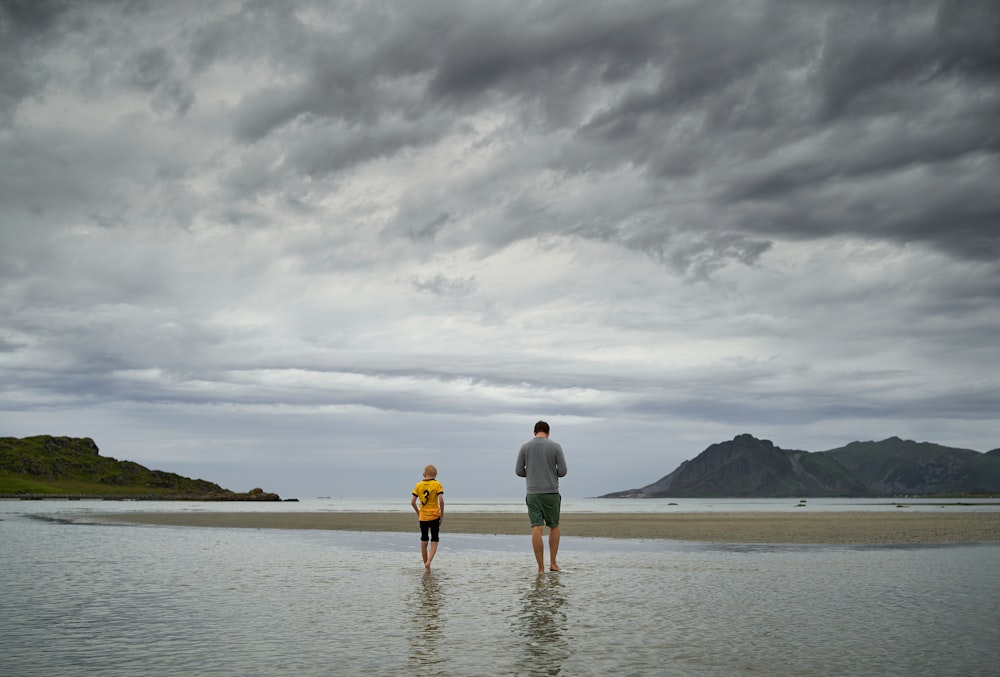 man and woman holding hands while walking on beach during daytime