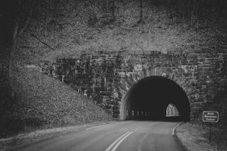 grayscale photo of tunnel road