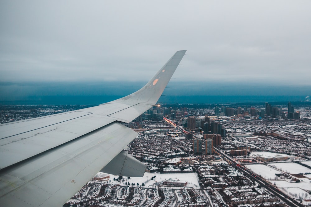 white airplane wing over city during daytime