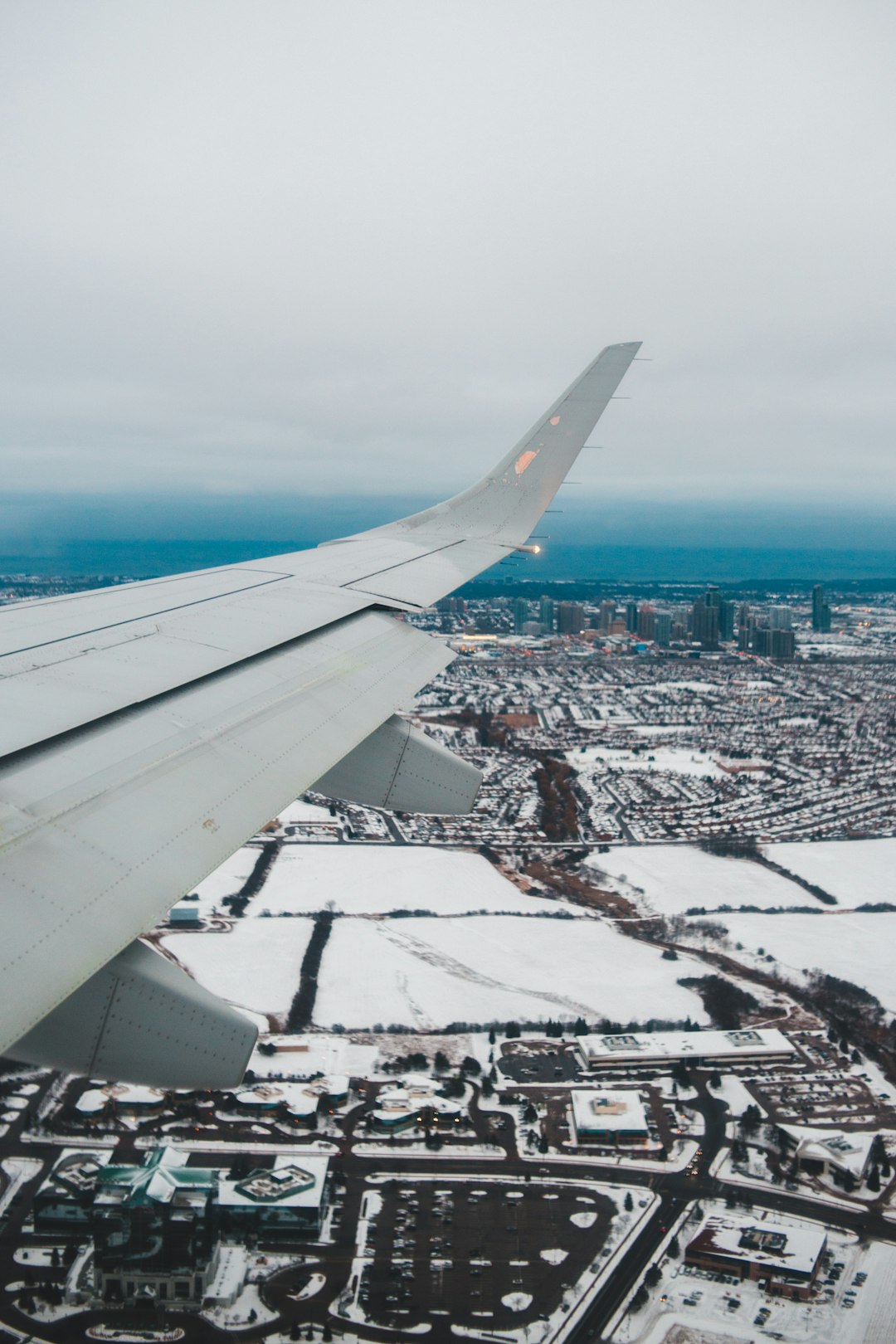 white airplane wing over city during daytime