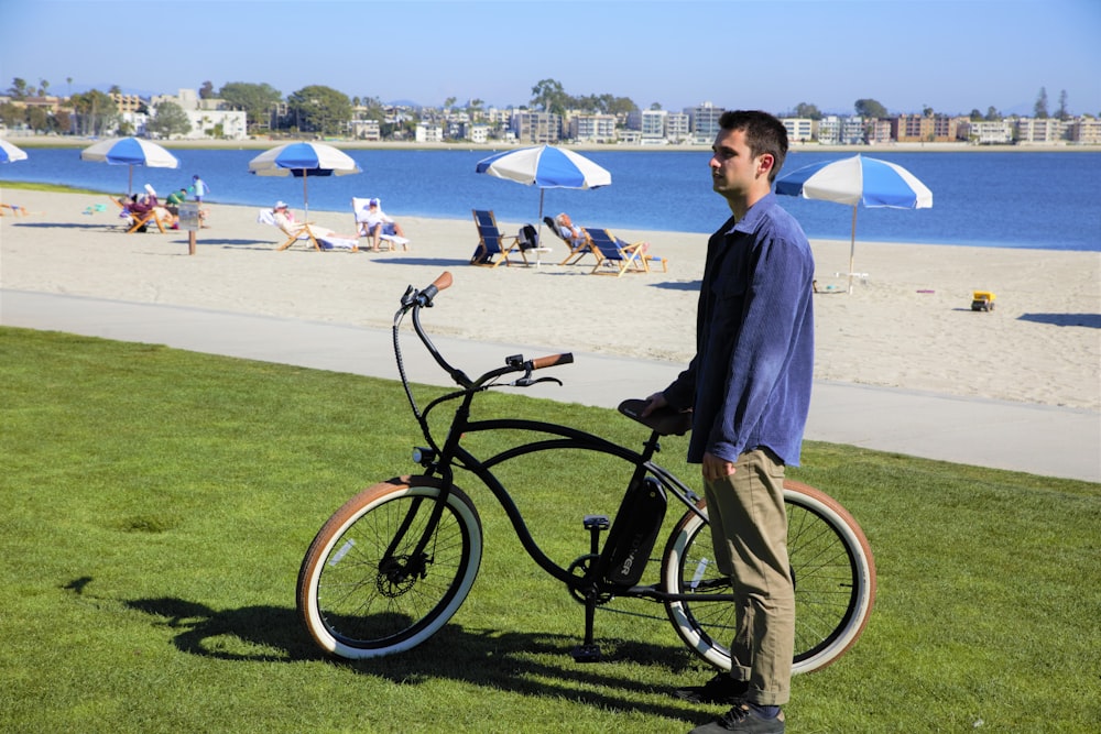 파란 드레스 셔츠를 입은 남자가 낮에 푸른 잔디밭에서 검은 자전거를 타고