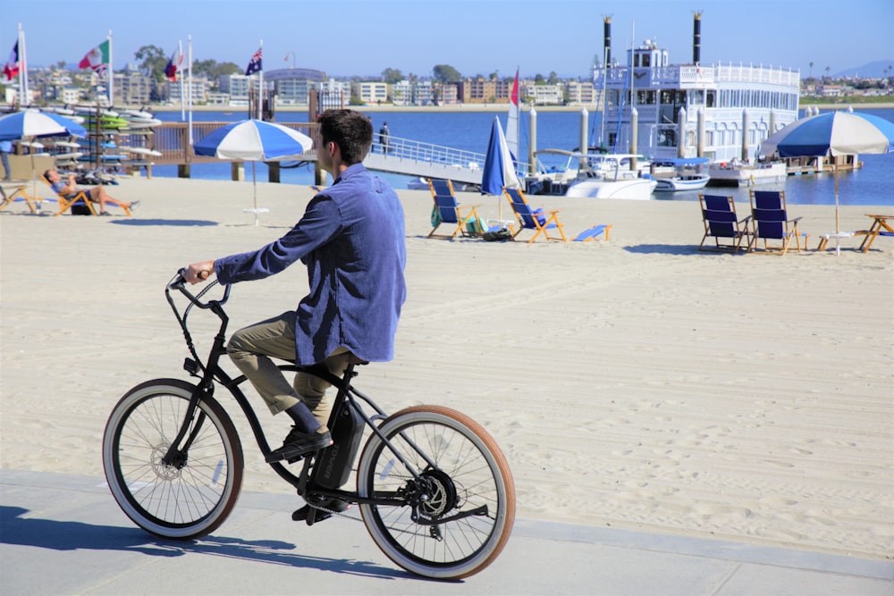 man in white dress shirt riding on black bicycle on white sand during daytime