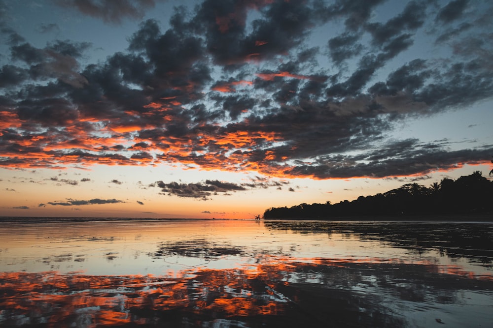 body of water under cloudy sky during sunset