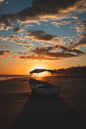 blue boat on beach during sunset