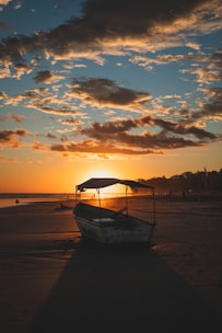 blue boat on beach during sunset