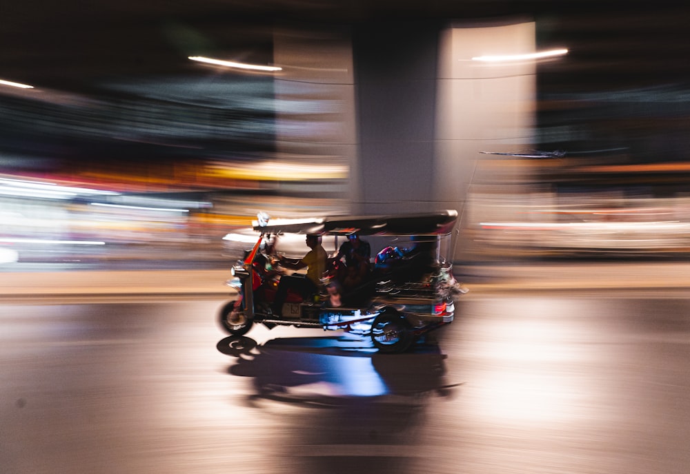 man in black jacket driving blue and black auto rickshaw