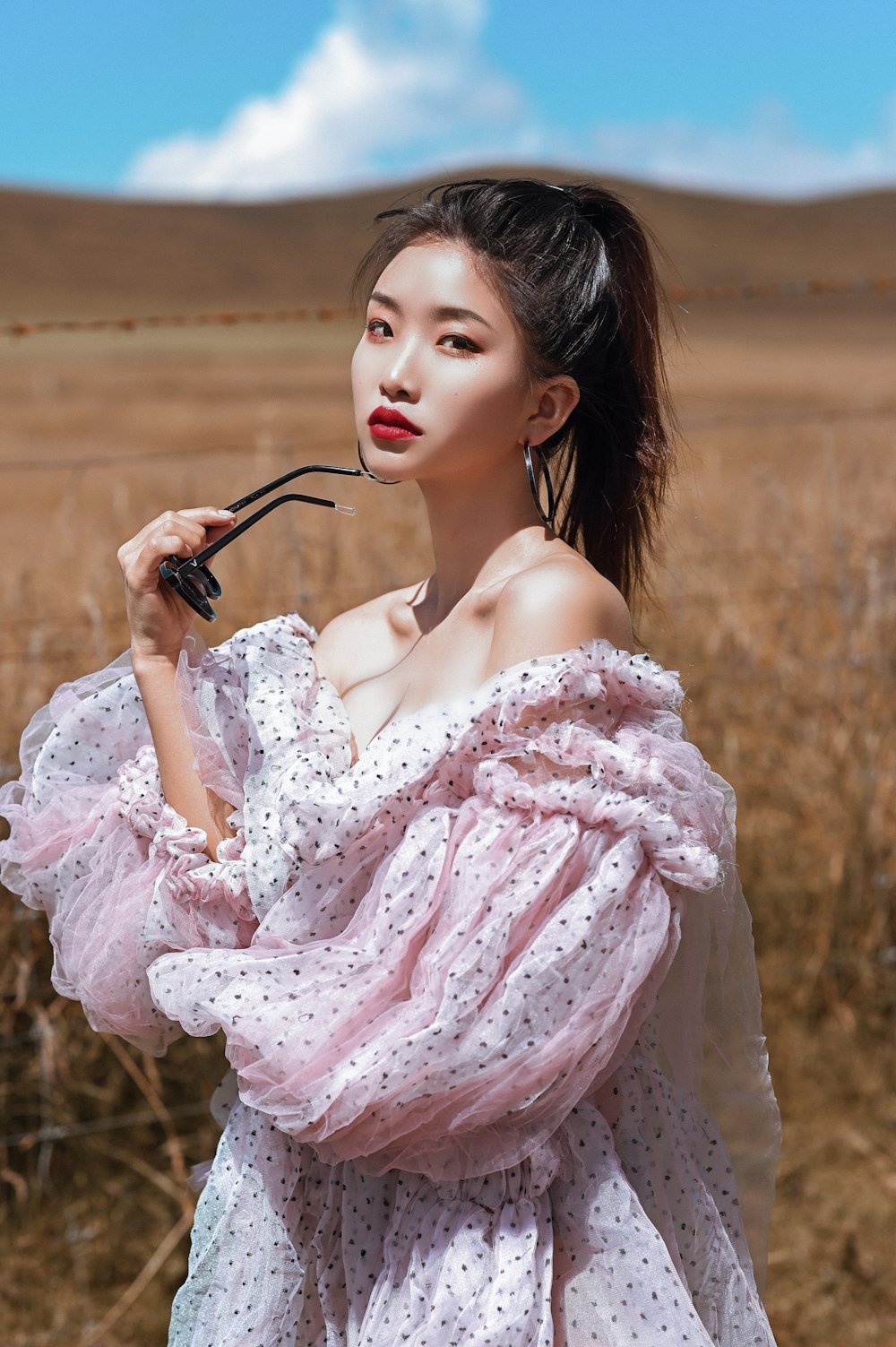 woman in pink floral dress holding black sunglasses