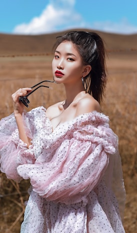 woman in pink floral dress holding black sunglasses