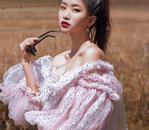 woman in pink floral dress holding black sunglasses