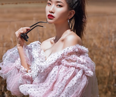 woman in pink floral dress holding black sunglasses