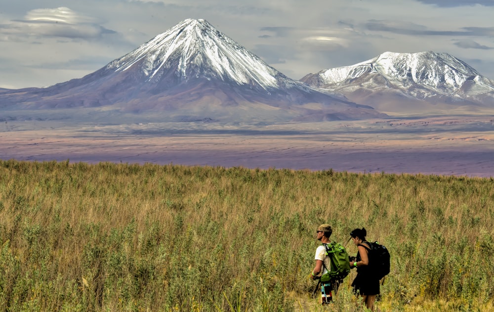 man and woman sitting on grass field near mountain during daytime