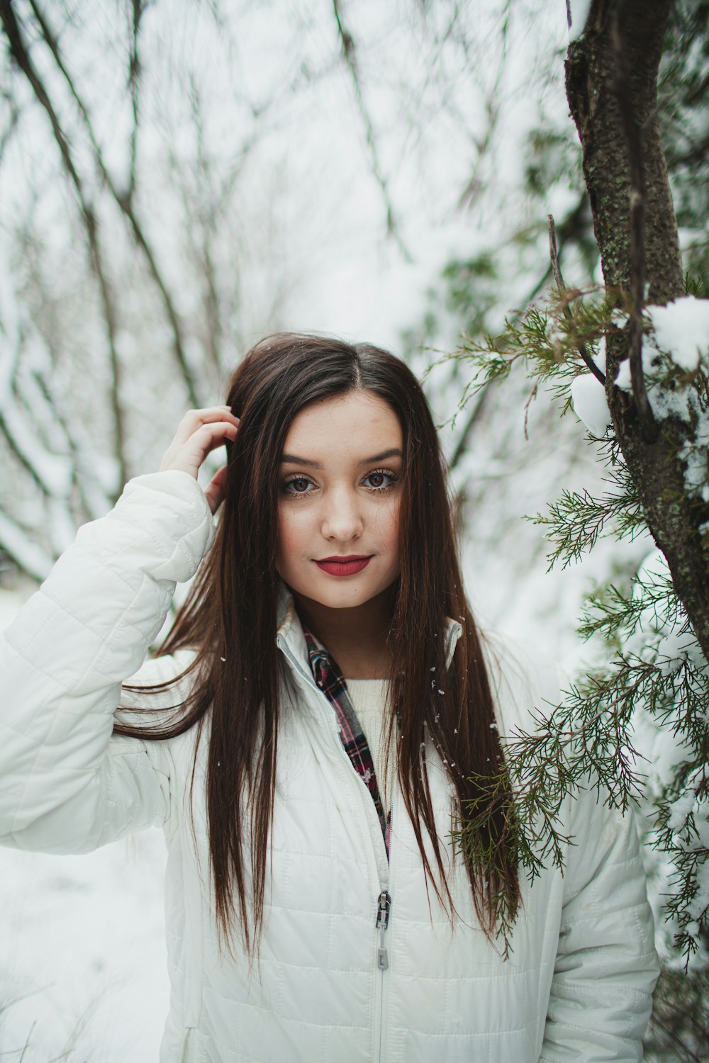 woman in white long sleeve shirt standing near green tree during daytime