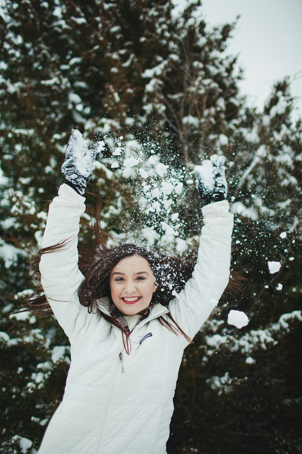 girl in white jacket standing near tree with snow