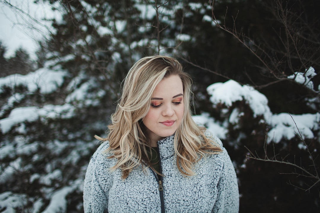 woman in gray cardigan standing near trees during daytime