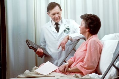 man in white button up shirt holding black tablet computer patient google meet background